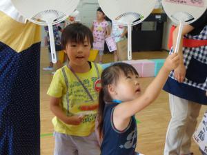 年長児が作ったうちわを観察している子供の写真