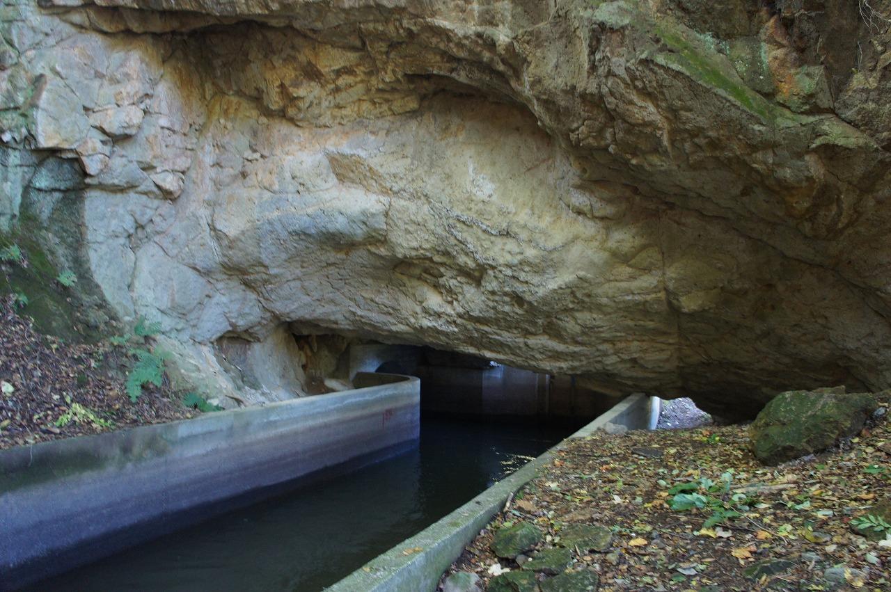 400年前に摺上川の左岸の崖の岩を削って木製の樋を掛けて作られた素掘りの隧道の写真