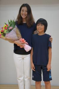 花束を贈られて写真を撮影する寺川さんと児童の写真