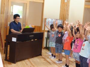 先生が電子ピアノを演奏して、園児たちが元気よく歌っている写真