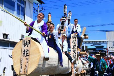 御柱里曳き祭で「御柱」と書かれてた大木の上に男性が乗っている写真