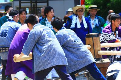 男の人たちが木の棒がついた装置を押して回している写真