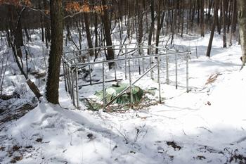 鉄条網に囲まれシートに包まれた簡易水道の水源地の写真