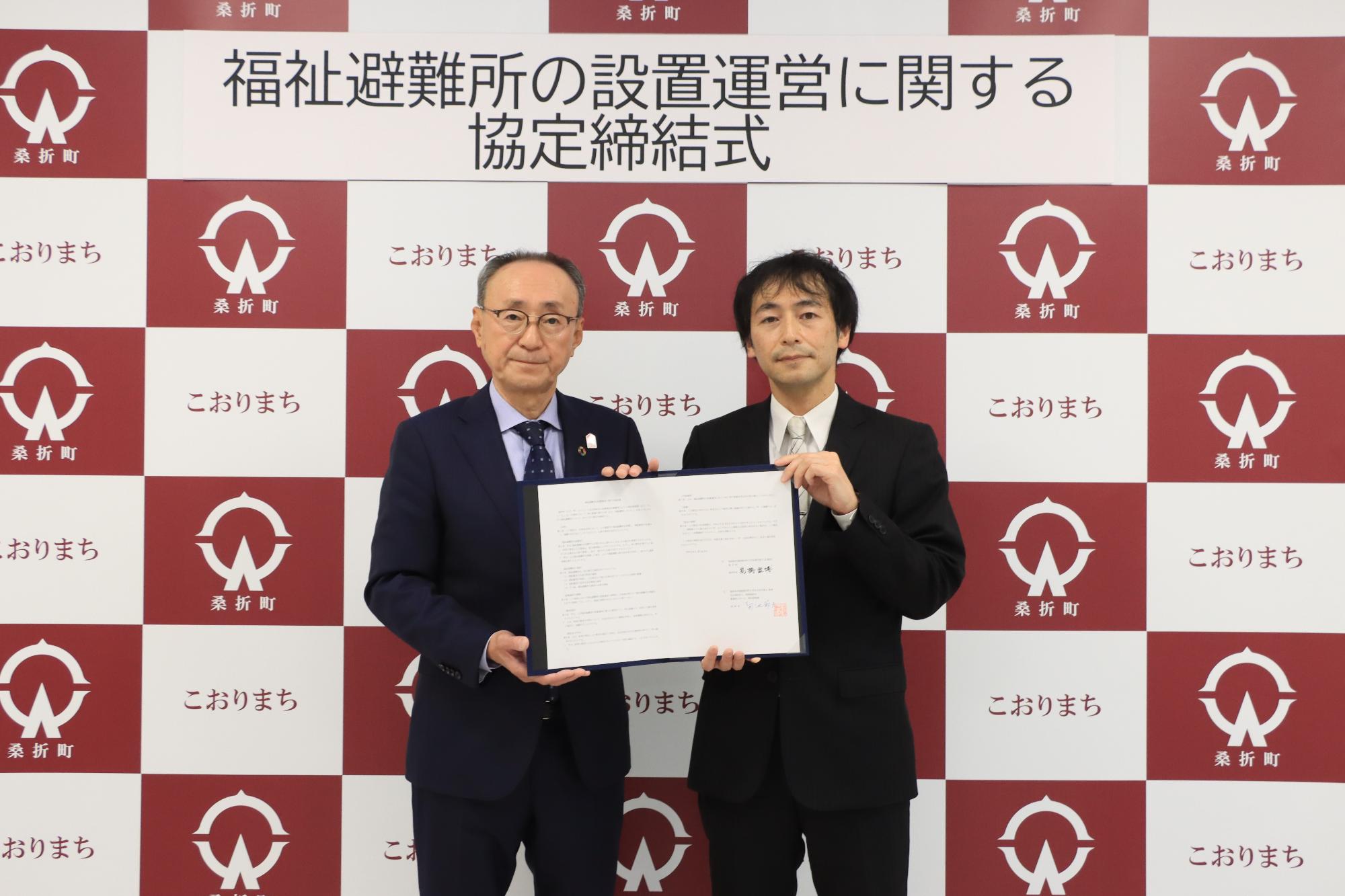 協定書を手にする（左から）高橋町長、社会福祉法人緑風福祉会の熊谷常務理事の写真